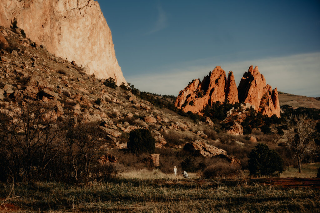"Nick kneeling to propose to Callie on a quiet trail at Garden of the Gods, captured from a distance with a telephoto lens."