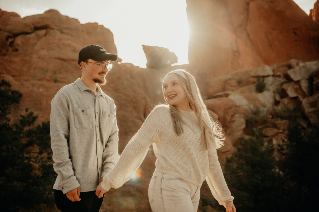Callie and Nick embracing joyfully after the proposal, with the red rock formations of Garden of the Gods in the background
