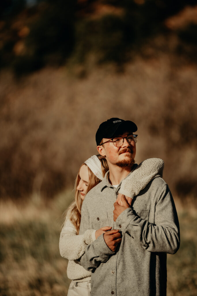 Callie posing for a portrait during a morning photo session at Garden of the Gods, unaware of the upcoming surprise proposal.Callie holding Nick from behind as they embrace enach other