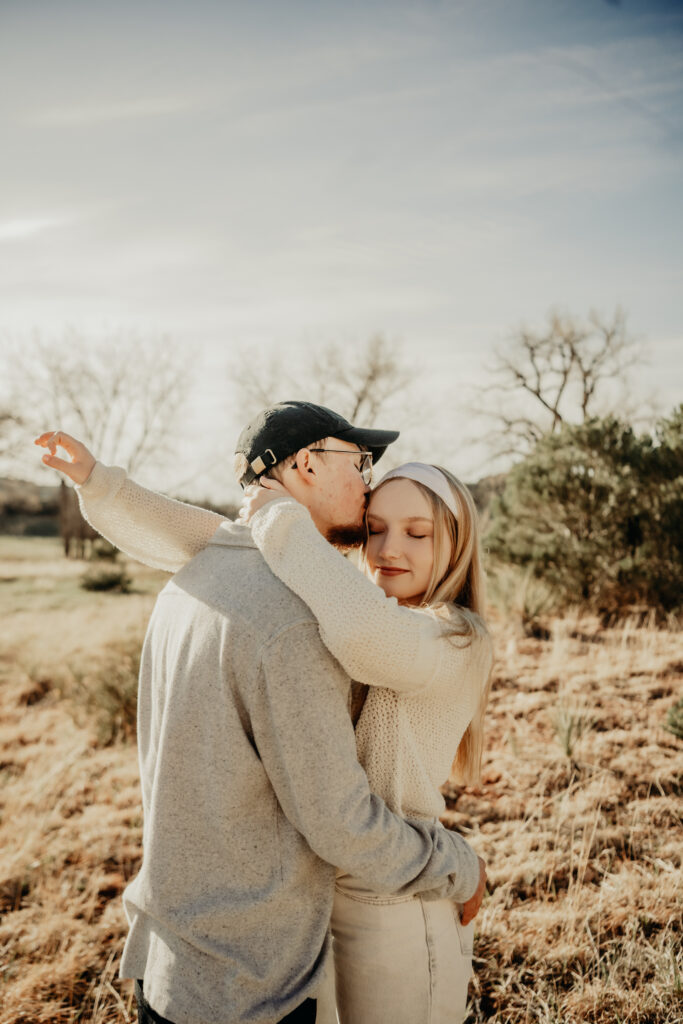 Callie and Nick embracing romantically after the proposal, with the red rock formations of Garden of the Gods in the background
