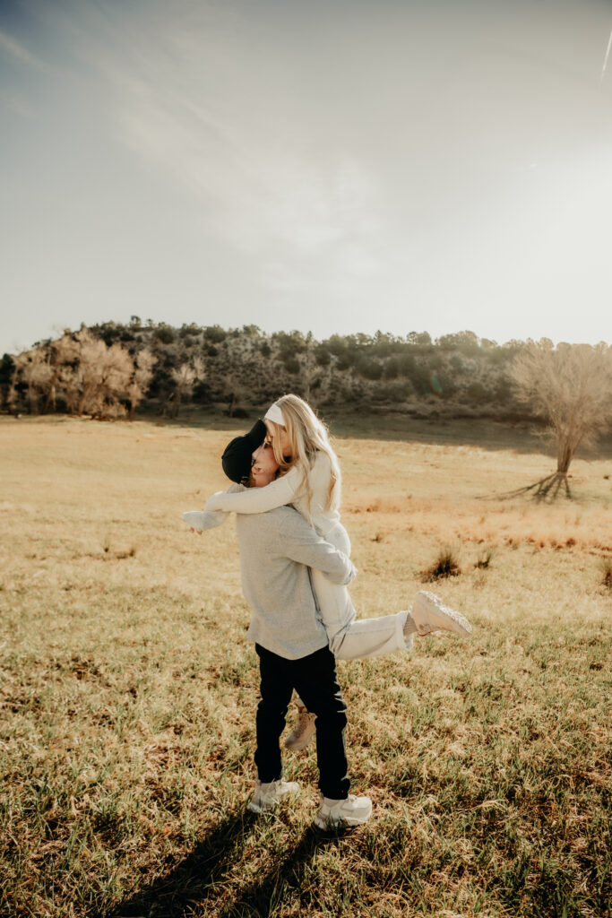 Callie posing for a portrait during a morning photo session at Garden of the Gods, unaware of the upcoming surprise proposal.Nick picking her up and spinning her around in teh meadow. 