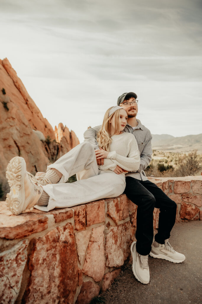 Epic pose of Callie and Nick posing on the brick wall with the Garden of the Gods behind them