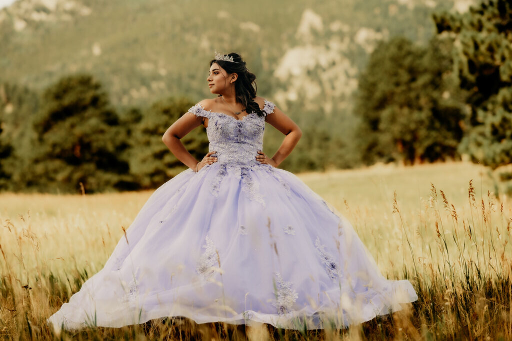 Quinceañera portrait of Natalia in a lavender purple ball gown standing with a tiara in an open field in Evergreen, Colorado