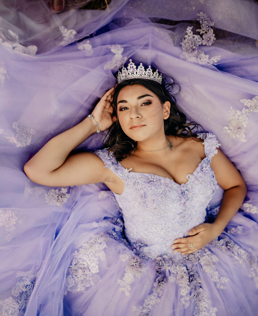 Quinceañera portrait of Natalia in a lavender purple ball gown standing with a tiara in an open field in Evergreen, Colorado