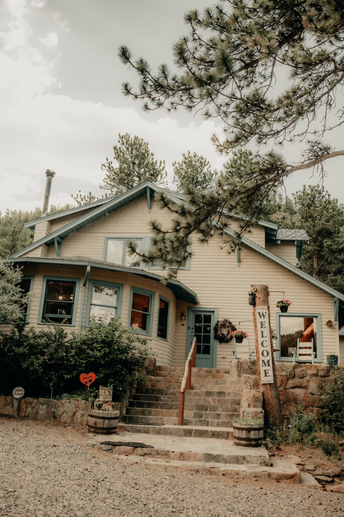 The entrance and main building with the welcome sign at Romantic Riversong Inn in Estes Park
