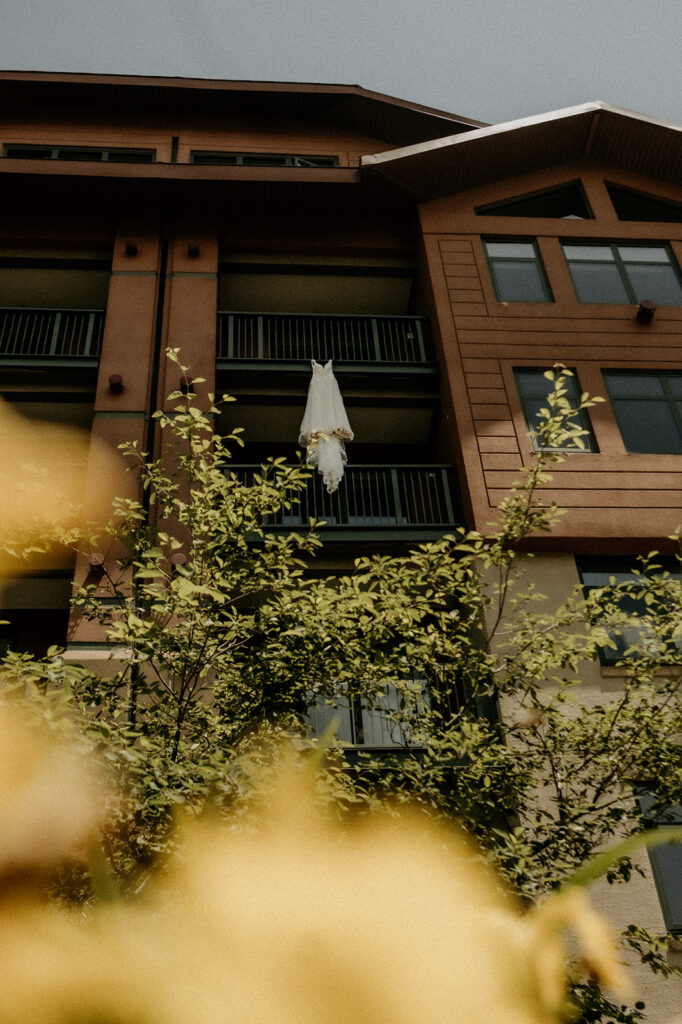 brides dress hanging from the hotel room balcony featuring aspen trees