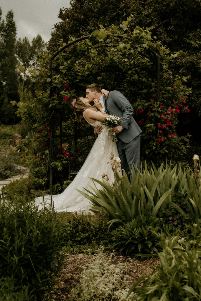 newly wed portraits under the floral arch at  Yampa River Botanic Gardens
