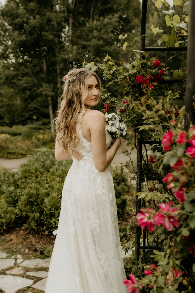 bride posing like the model and star she is under the floral arch at the  Yampa River Botanic Gardens