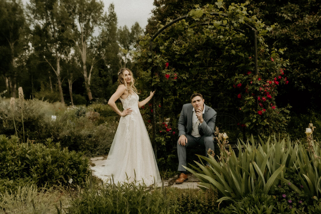 bride and groom posing for a more editorial moody vogue shot under the floral archway at the Yampa River Botanic Gardens
