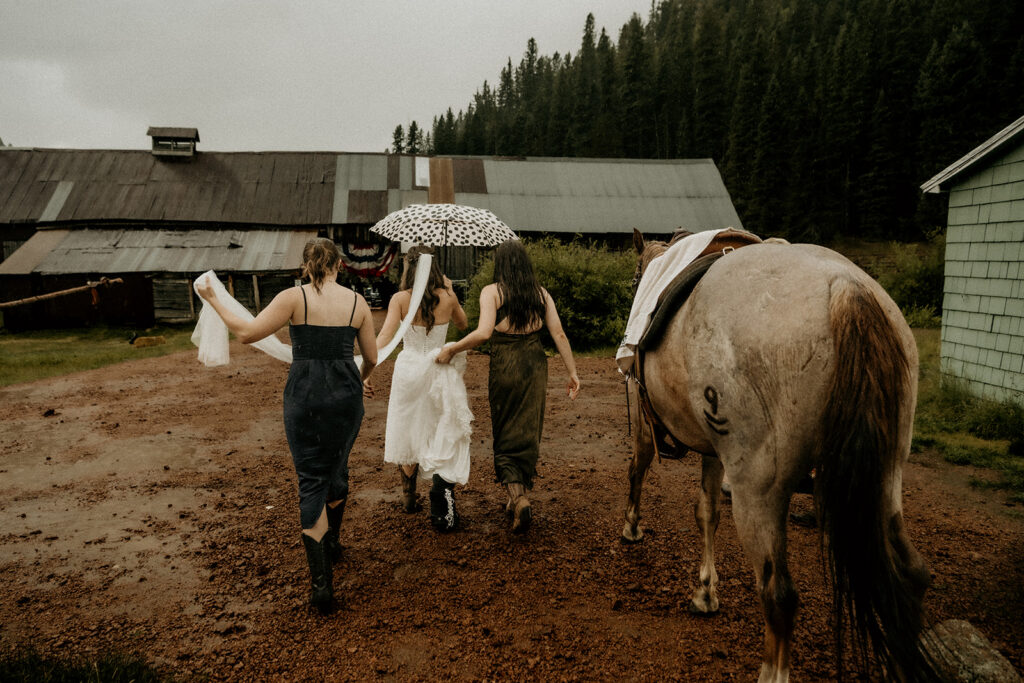 bride walking to the horse barn in the rain to have her first look
