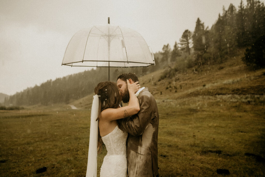 newly weds kissing in the rain after saying i do at their mountain wedding on the elk glade ranch