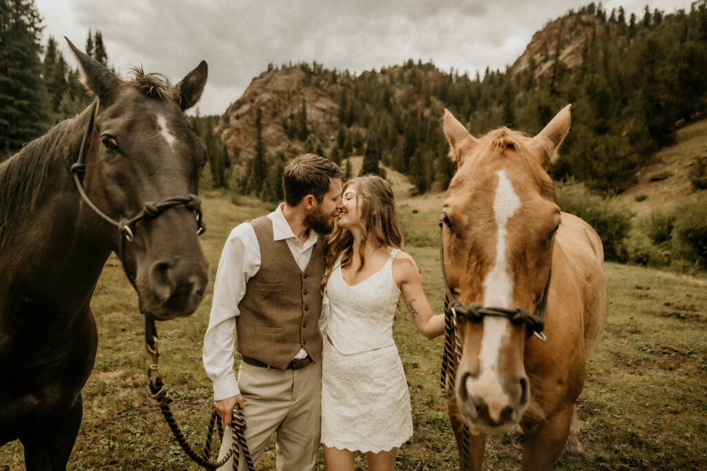 newly weds kissing while holding horses at the elk glade ranch in cascade colorado